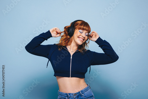 фотографія Happy young woman dancing while listening to music on headphones in a studio