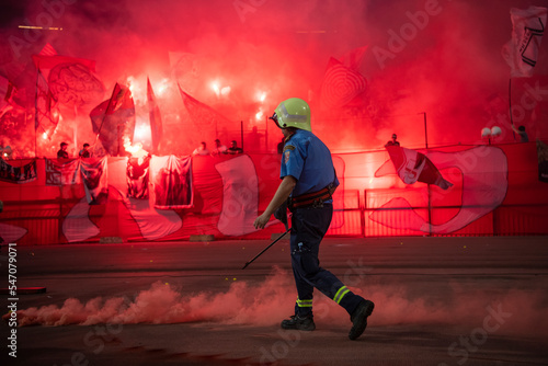 Firefighter with uniform in the Stadium during the soccer event removing torches. Torches and atmosphere during Eternal soccer derby in Belgrade, Serbia 22.05.2022 photo