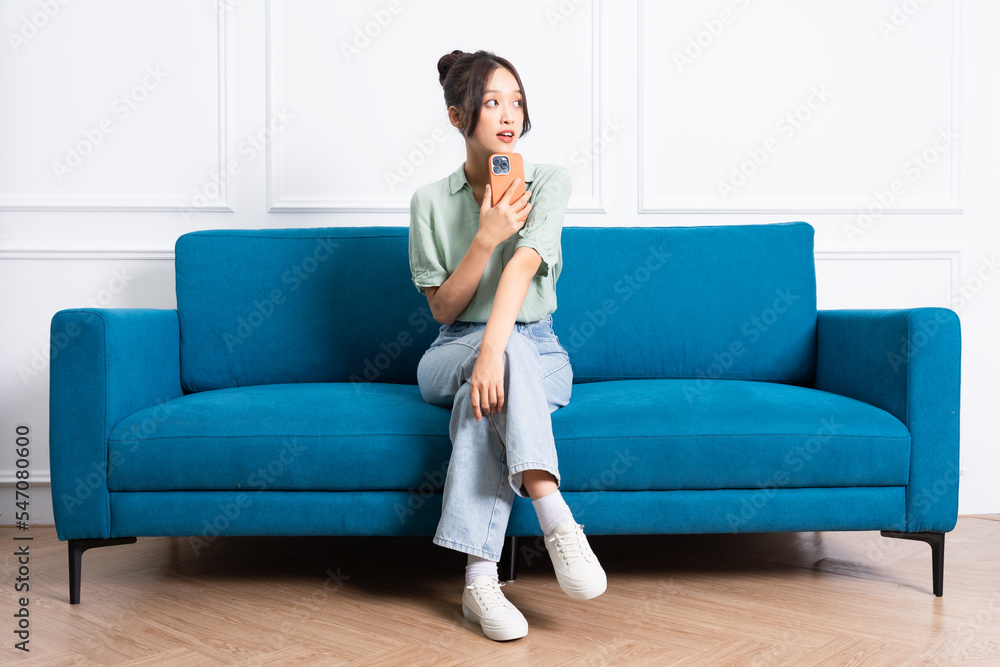 image of young Asian girl sitting on sofa at home image of young Asian girl sitting on sofa at home