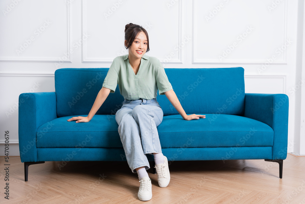 image of young Asian girl sitting on sofa at home image of young Asian girl sitting on sofa at home