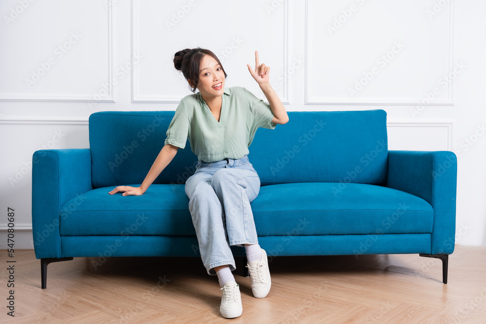 image of young Asian girl sitting on sofa at home image of young Asian girl sitting on sofa at home