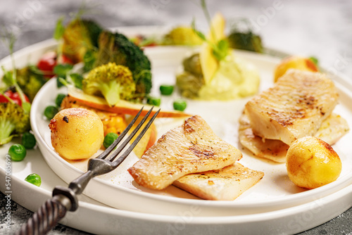 Wallpaper Mural Close-up Baked sea fish fillet with vegetables. Tilapia fillet with broccoli, cherry tomatoes, fried potatoes, green peas and lettuce. Sea food on a white plate. Mediterranean Diet. Selective focus Torontodigital.ca