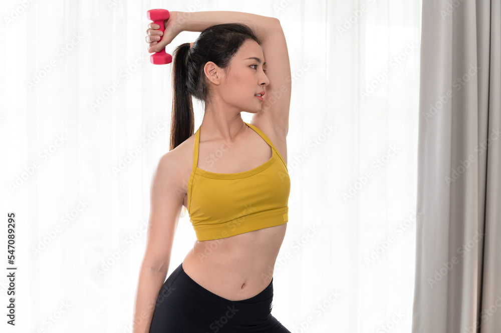 Asia sport woman holding dumbbell in living room at home	