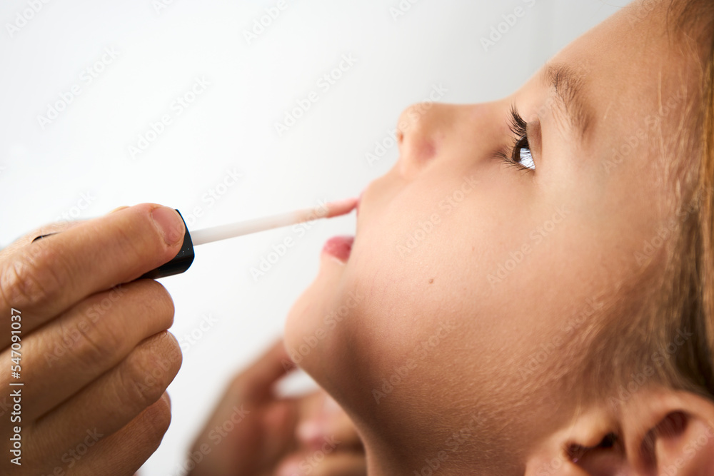 Little girl applying makeup, white background