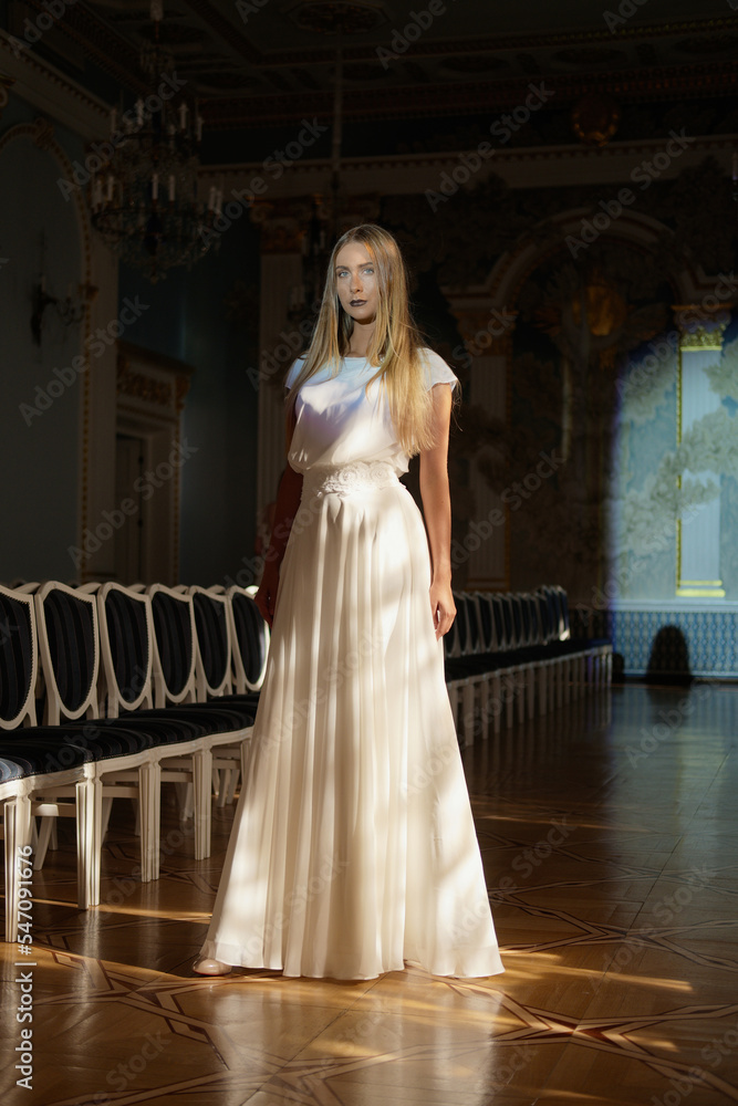 Fototapeta premium Full length portrait of beautiful young woman in ivory silk dress