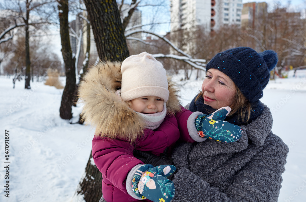 Grandmother, mother and daughter are walking in the winter city park on Christmas and New Year holidays. Parent and little child having fun outdoors Grandmother, mother and daughter are walking in the winter city park on Christmas and New Year holidays. Parent and little child having fun outdoors