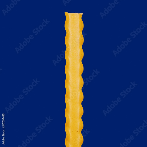 Close up still life raw reginette pasta with ruffled edges on blue background
 photo