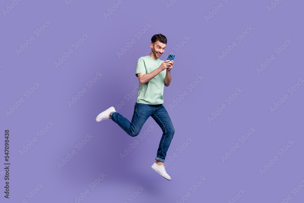 Full length photo of cheerful crazy man use modern gadget look telephone read good news isolated on purple color background