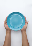 Male hands are holding a blue plate on a white isolated background