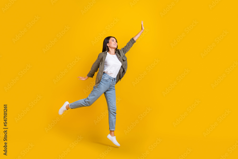 Full length photo of young japanese businesswoman jumping air raise hand up look mockup want catch luck isolated on yellow color background Full length photo of young japanese businesswoman jumping air raise hand up look mockup want catch luck isolated on yellow color background