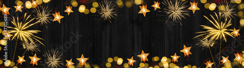 New Year Chrsitmas celebration decoration background banner panorama - Frame made of golden star light chain, firework and bokeh lights on dark black wooden boards wall texture