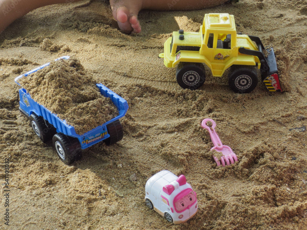 Transportation toys played by a boy in the beach. Heave vehicle toys on the beach Transportation toys played by a boy in the beach. Heave vehicle toys on the beach