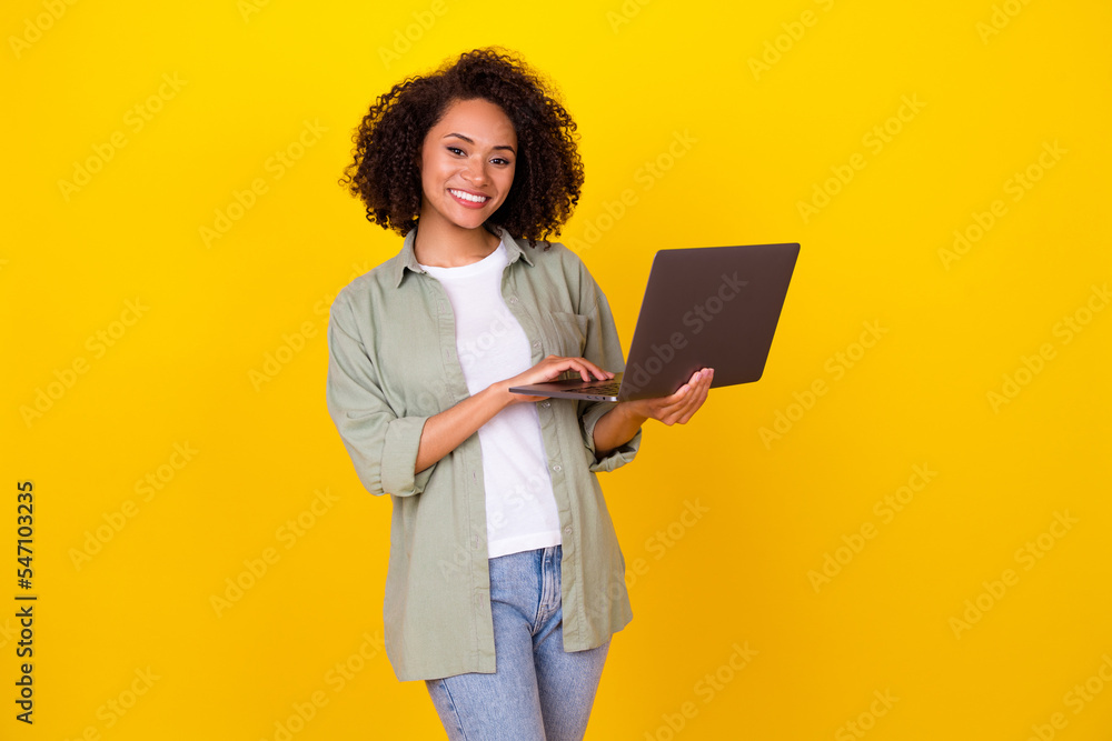 Photo of ceo curly millennial brunette lady hold laptop wear grey shirt jeans isolated on yellow color background Photo of ceo curly millennial brunette lady hold laptop wear grey shirt jeans isolated on yellow color background