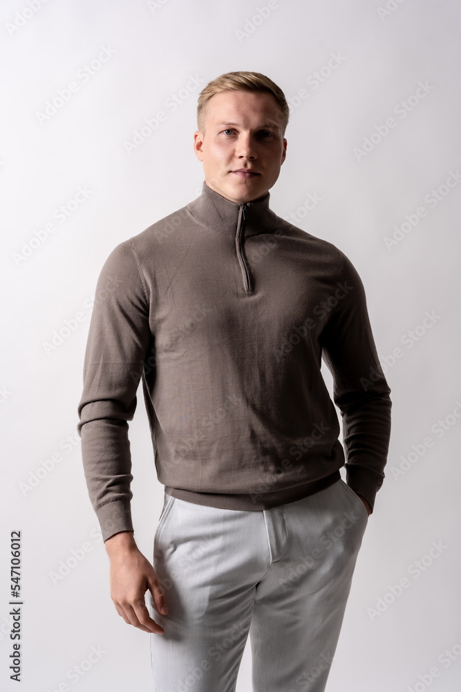 Portrait of an attractive blond german model with a brown sweater on a white background, looking at the camera Portrait of an attractive blond german model with a brown sweater on a white background, looking at the camera