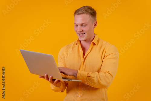 Caucasian blond businessman man on a yellow background, portrait with a laptop smiling, ceo