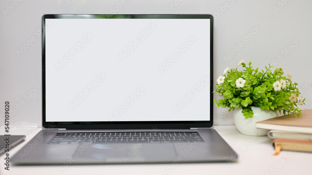 Fototapeta premium Notebook laptop white screen mockup is on the table with decor. close-up workspace
