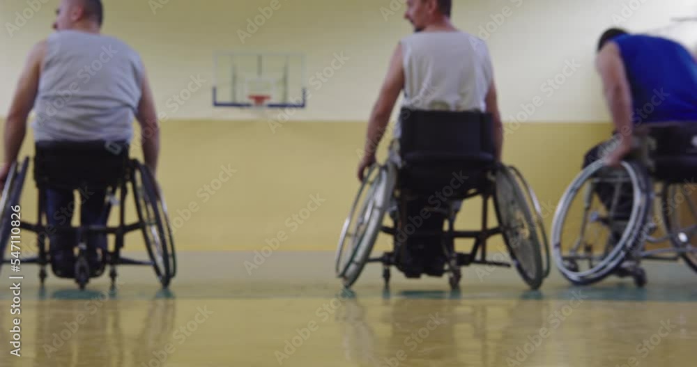 Close-up of a sporty person with disability sitting in a wheelchair playing a basketball team game in the school gym court. Selective focus. Close-up of a sporty person with disability sitting in a wheelchair playing a basketball team game in the school gym court. Selective focus.