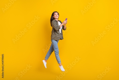 Fototapeta Naklejka Na Ścianę i Meble -  Full length photo of young influencer vietnamese jump air businesswoman hold phone remote work freelancer isolated on yellow color background