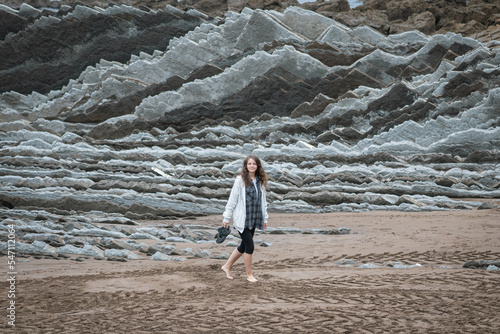 Girl walks on the Itzurun Beach in Zumaia, Basque Country, Spain. Flysh rocks.