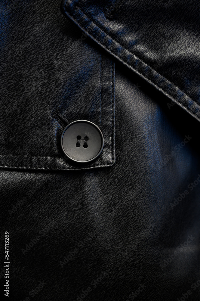 Close-up of a black button on a leather coat. Button on leather fabric Close-up of a black button on a leather coat. Button on leather fabric