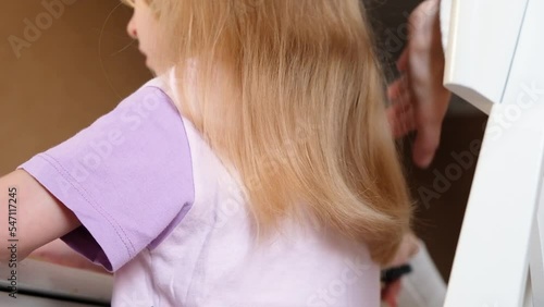 Hairdresser Trimming the Ends of a Blond Girls Hair. Mother doing daughter's haircut at home photo