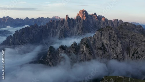 Mysterious sunrise drone shot of clouds covering Cadini Di Misurina Mountain range in the Dolomites, Italy. photo