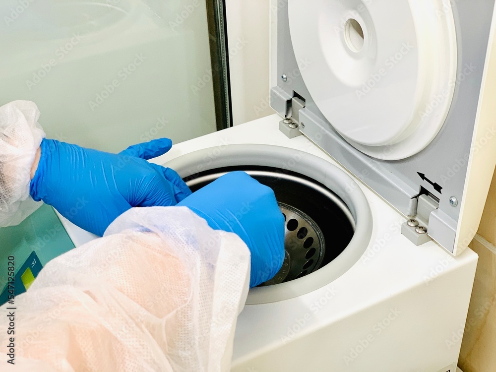 Technician loading a sample to centrifuge machine in the medical or scientific laboratory Technician loading a sample to centrifuge machine in the medical or scientific laboratory