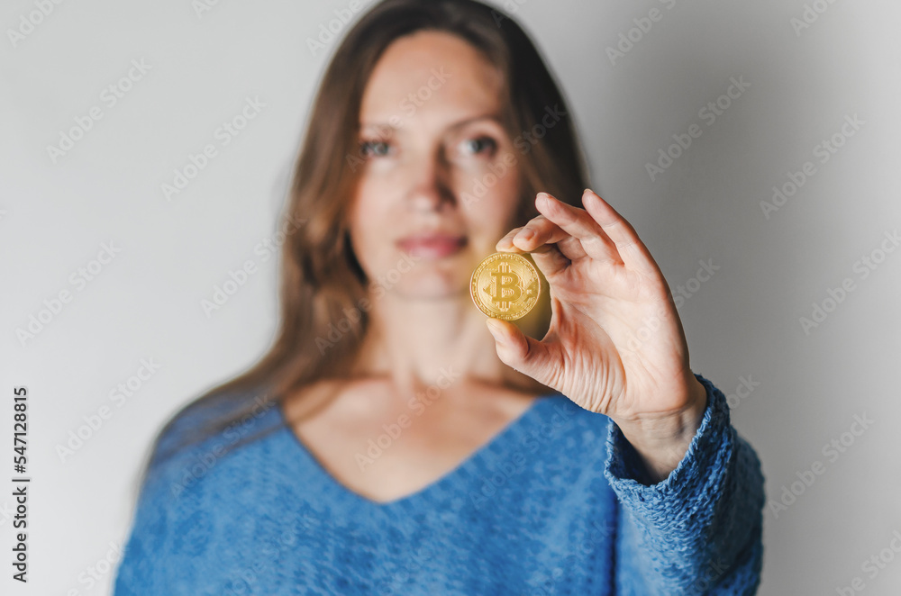Portrait of woman in casual clothes looking at camera holding bitcoin, future currency, isolated on white background in studio. People lifestyle concept. Portrait of woman in casual clothes looking at camera holding bitcoin, future currency, isolated on white background in studio. People lifestyle concept.