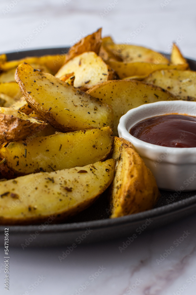 Oven roasted potatoes with skins, sliced, with sauces close-up Oven roasted potatoes with skins, sliced, with sauces close-up