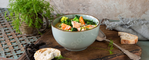 bowl of creamy soup with salmon and broccoli on the table