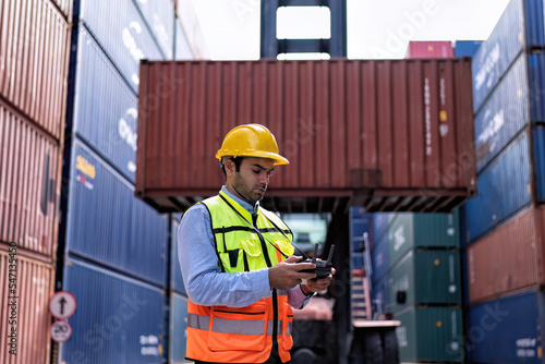 Engineer working in container storage yard fly drone looking location layout prepare to delivery