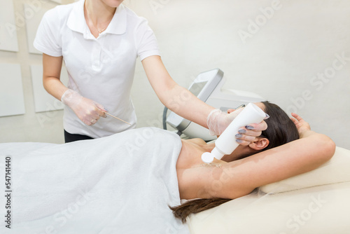 The cosmetologist applies a special transparent gel to the skin of the armpit.