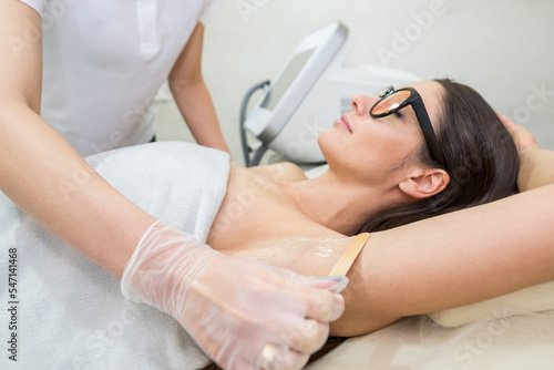 A beautician in white latex gloves applies a cooling contact gel