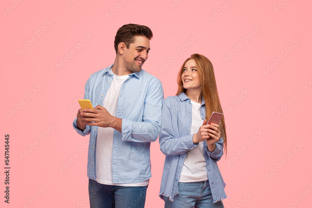 Cheerful couple using smartphones together Cheerful couple using smartphones together