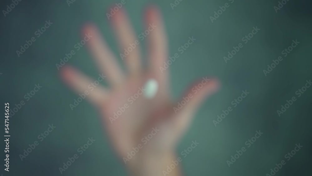 Throwing up and catching white spinning medicine pill using hand over green spotted table surface in bright studio macro slow motion Throwing up and catching white spinning medicine pill using hand over green spotted table surface in bright studio macro slow motion