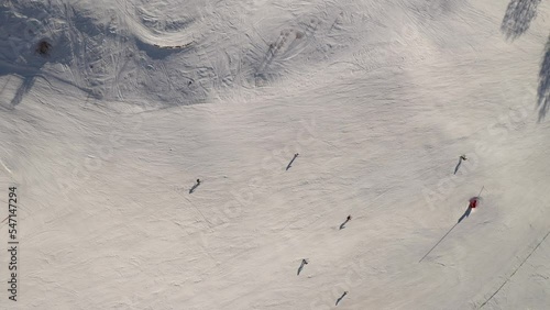 Top down aerial drone view of skiers skiing down the slope photo