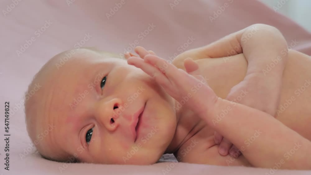 Portrait of a newborn baby. Caucasian child laying on the bed and looking around. Slow motion shot Portrait of a newborn baby. Caucasian child laying on the bed and looking around. Slow motion shot