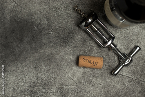 Tokaji wine. Bottle, corkscrew and cork on a black background.