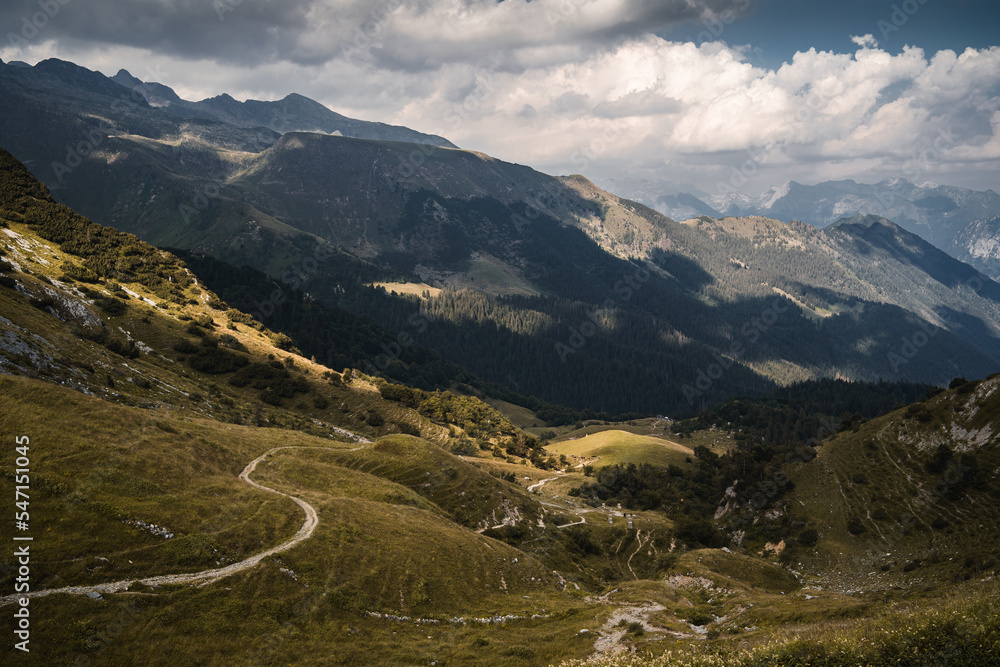 Fototapeta premium Spots of sunlight over the green hills and peaks of the Orobie Alps, Northern Italy