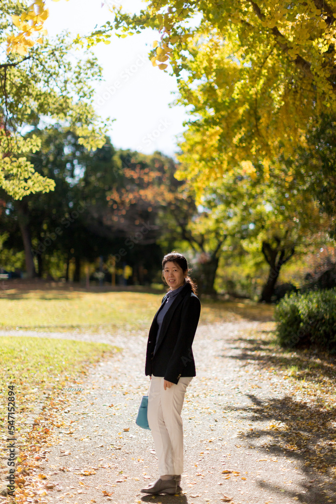 秋の公園で散歩している中年女性の姿 秋の公園で散歩している中年女性の姿