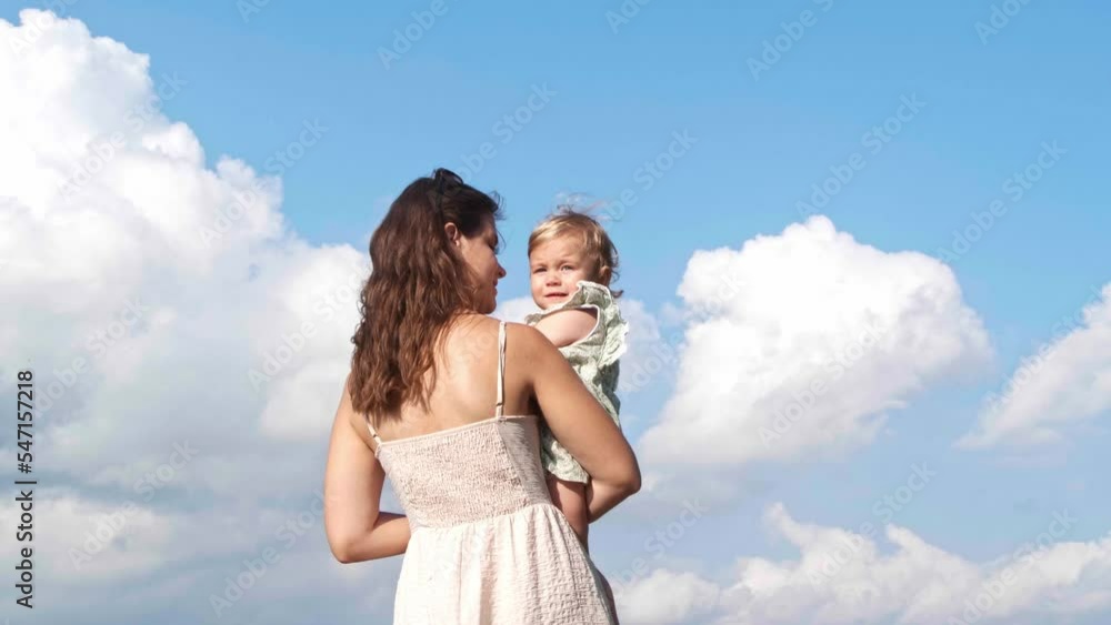 Mother holding her daughter in arms outdoors Mother holding her daughter in arms outdoors