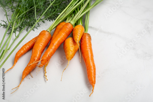 Close up of bunch of fresh carrots fresh vegetables on marble surface copy space