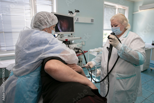 A female doctor holds an endoscope during a gastroscopy for a hospital patient. Medical office for diagnosing abdominal pain.