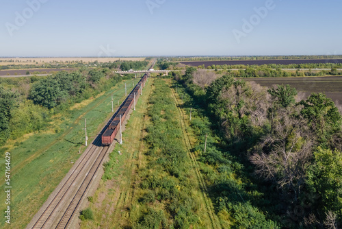 Freight train wagons passing through countryside in the afternoon, Aerial view