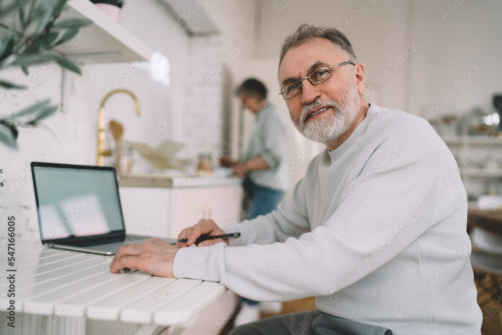 Senior man sitting at table and working on laptop Senior man sitting at table and working on laptop