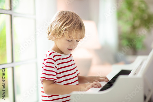 Child playing piano. Kids play music. © famveldman