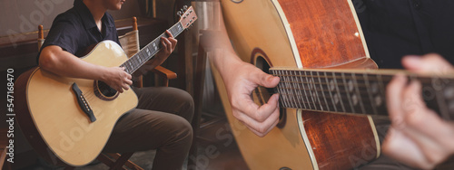 Musician is sitting and playing an acoustic guitar with panorama background. Concept of musical class, School course study banner, poster background, widescreen for advertisement. 