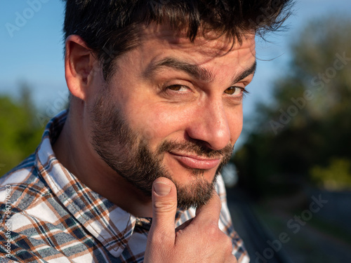 Retrato de homobre con expresión de confianza, vanidad, sosteniendo su barbilla con la mano. photo