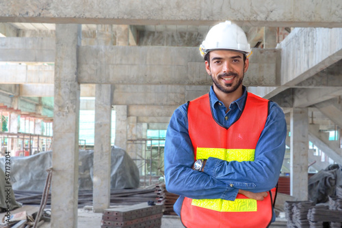 Portrait young handsome Middle Eastern engineer construction background. Saudi skilled professional  work planning. Multi-ethnic civil engineering group unite cooperate same goal. banner copy space.