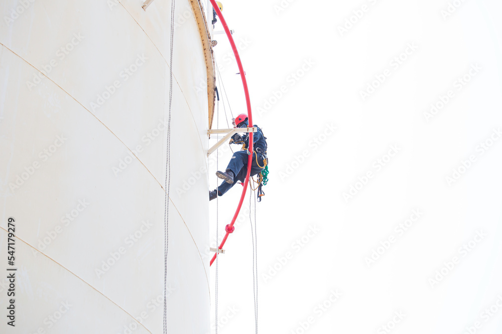 Top view pic of industrial rope access welder working at height wearing  harness, helmet safety equipment rope access inspection of thickness  storage tank Stock Photo